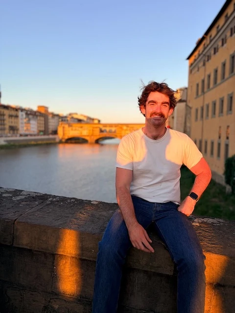 Nathan sitting on the bridge looking out to the Ponte Vecchio in Florence.